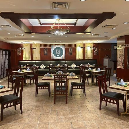 Safir Hotel Cairo Giza Bagian luar foto The photo shows the interior of a restaurant. The space features a combination of warm wood tones and elegant decorations. There are several dining tables arranged throughout, each set with plates, cutlery, and decorative napkins. The walls are adorn