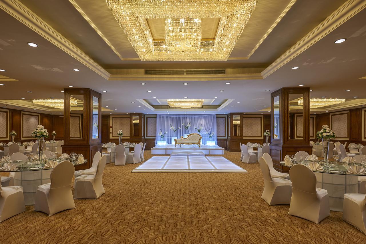 Safir Hotel Cairo Giza Bagian luar foto The photo shows an elegantly decorated event space. The room features a beautiful chandelier hanging from the ceiling, providing a warm glow. In the center, there is a raised platform that appears to be set up for a ceremony or celebration. Surroundi