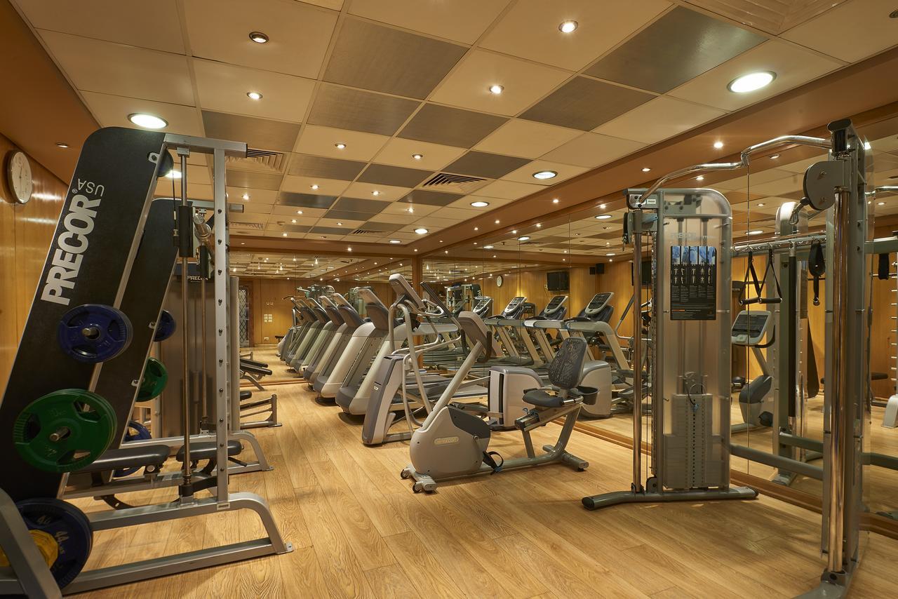 Safir Hotel Cairo Giza Bagian luar foto The photo shows a well-equipped gym with various exercise machines. There are several cardio machines lined up, including treadmills, stationary bikes, and elliptical trainers. Strength training equipment is also present, including a multi-functional