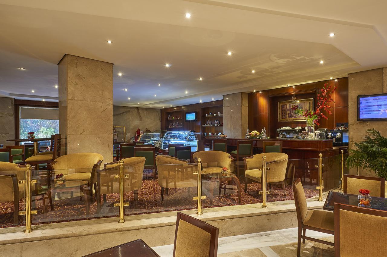 Safir Hotel Cairo Giza Bagian luar foto The photo shows the interior of a café or restaurant. It features a well-lit space with modern decor, including comfortable seating arranged around small tables. There are elegant, plush chairs and a section that appears to be a counter or bar area, 